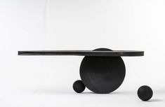 two black balls and a table with one on it's side, in front of a white background