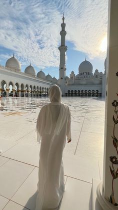 a person in a white robe walking towards a building