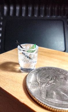 a small glass filled with water next to a coin