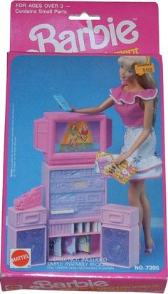 a barbie doll plays with her toy kitchen set in the box on the carpeted floor