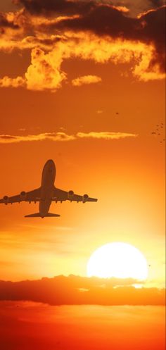 an airplane is flying in the sky at sunset