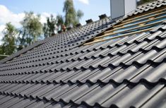 the roof of a house with metal shingles on it and trees in the background