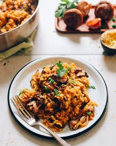 a white plate topped with rice covered in mushrooms and garnished with parsley