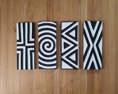 three black and white paintings on a wooden floor