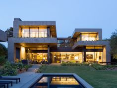 a large modern house with lots of windows on the front and side of it at night