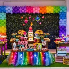 a rainbow themed dessert table with lots of balloons