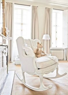 a white rocking chair with a teddy bear sitting on it in front of a window