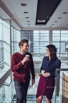 a man and woman walking down the stairs in an office building - stock photo - images