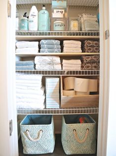 an organized closet with baskets, towels and other bathroom items on shelves next to each other