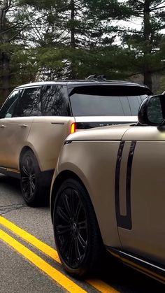 two cars parked side by side on the road with trees in the backgroud