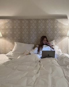 a woman laying in bed using a laptop computer