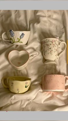 there are many different cups on the bed