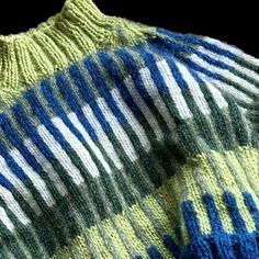 the sweater is knitted and has blue, green, and white stripes on it