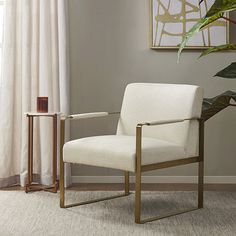 a white chair sitting in front of a window next to a plant