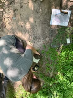 a woman sitting on the ground next to a tree