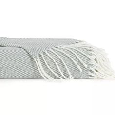 the grey and white blanket with fringes is folded up on top of each other