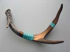 an antler with turquoise and brown beads on it's horns is displayed against a gray background