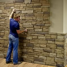 a man is working on a wall made out of stacked stone blocks in an office