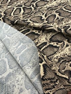 an up close shot of a snake skin pattern on a bed sheet with a blue and white pillow