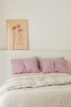 a bed with pink pillows and two vases on the wall above it in a bedroom