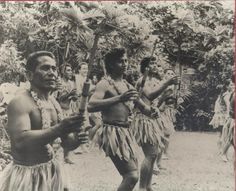 an old black and white photo of some men in native american clothing holding stick's