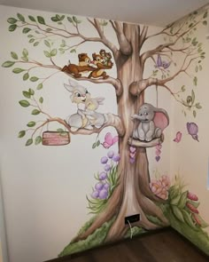 a child's room with a tree painted on the wall and various animals in it