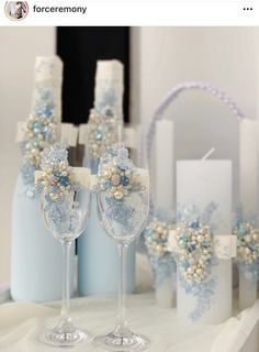 two wine glasses sitting on top of a table next to candles and flowers in vases