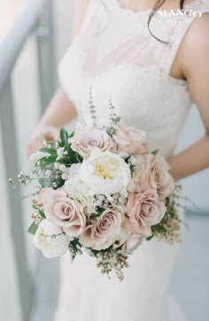 a bride holding a bouquet of pink and white flowers on her wedding day in front of the ocean