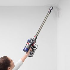 a woman is using a vacuum to clean the wall with her hand and arm,