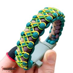 a hand holding a green, yellow and purple bracelet with braiding on the inside