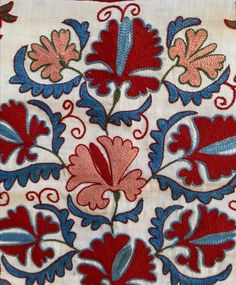 an embroidered cloth with red, blue and green flowers on it's edges is shown