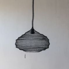 a black piece of wire hanging from a hook on the wall next to a white wall