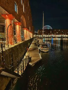 boats are docked in the water next to buildings with christmas lights on them at night