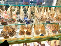 an ice cream display case filled with lots of different types of cones and toppings