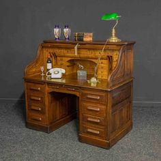 an old fashioned desk with a green lamp on top