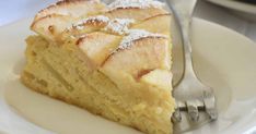 a piece of cake with powdered sugar on top sits on a white plate next to a fork