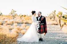 a man and woman in kilts standing next to each other on a dirt road