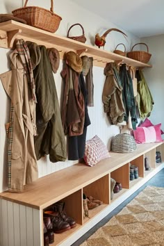 a bunch of coats and shoes hanging on a wall in a room with white walls