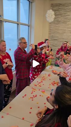 a group of people standing around a table with confetti on top of it