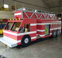 a red and white fire truck made out of legos sitting in a garage area