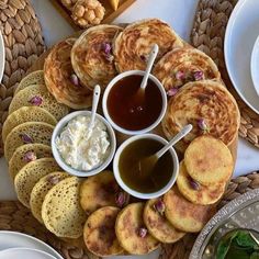 some pancakes and other food items on a table with breads, sauces and butter