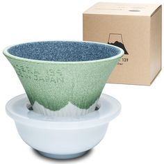 a green and white bowl sitting on top of a plate next to a cardboard box