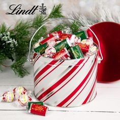 a bucket filled with candy sitting on top of a table next to a christmas tree