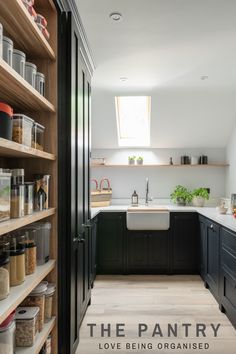 a kitchen with black cabinets and white counter tops is seen in this image from the hallway