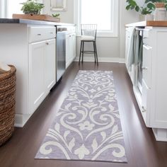 a kitchen with white cabinets and an area rug on the floor next to the stove