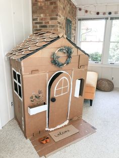 a cardboard house made to look like it has a wreath on top