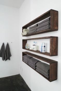 two wooden shelves holding towels and other bathroom items