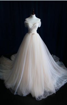 a white wedding dress on display in front of a dark background with sheer tulle