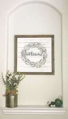 a white fireplace mantel topped with a potted plant next to a framed welcome sign