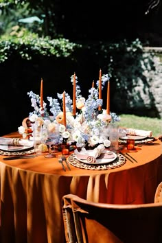 the table is set with orange linens and white flowers